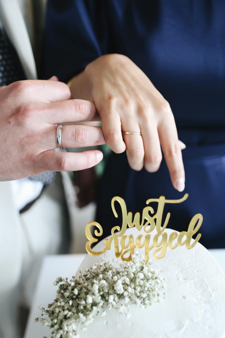 A couple holding hands and placing a wedding cake on top of a table