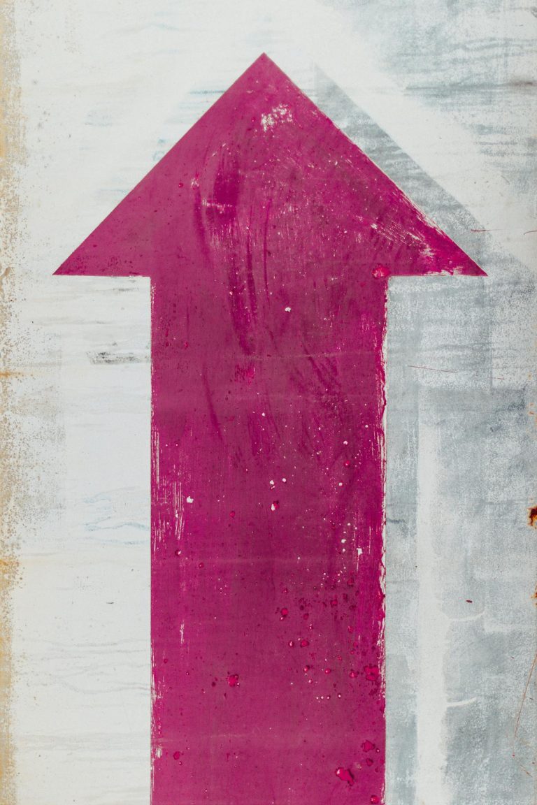 Painted Pink Up Arrow Sign on White Wall